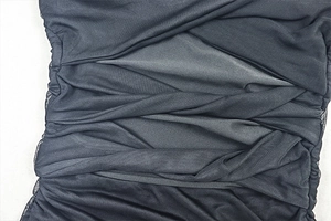 Détail de la texture en maille froncée noire de cette robe courte à manches longues
