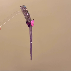 Detailed macro of purple butterfly hair clip with crystal accents and long chain tassels