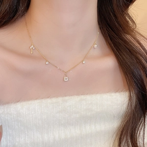 Detail shot of a gold-plated multi-pendant necklace featuring small key and lock charms