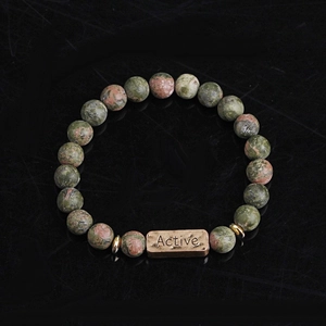Detailed macro view of natural unakite stone bracelet with bronze Active engraved plate