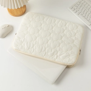 Detail of cream quilted laptop sleeve with heart stitching and smooth metal zippers