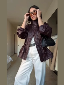 Detail of burgundy leather jacket featuring stand collar and elastic cuffs in street style