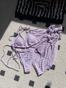Close-up of lavender seersucker bikini set with matching textured sarong on patterned rug