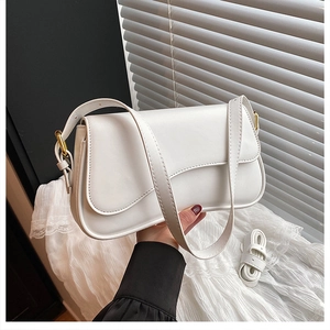 Detailed view of white leather shoulder bag with gold hardware and adjustable strap