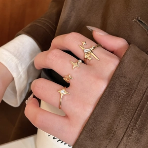 Detailed view of four stacked gold rings with star-shaped zircons on a model's hand