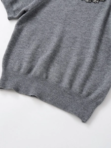 Detailed macro view of the grey knit top's ribbed hem and fine fabric texture