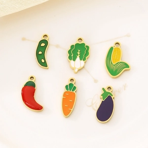 Colorful enamel vegetable pendants in stainless steel on a ceramic tray for DIY jewelry