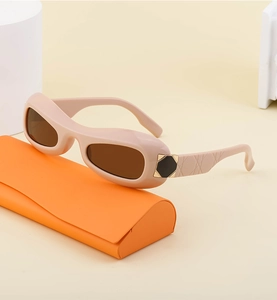 Detail of trendy oval sunglasses with tan frame, metal accents and orange leather case