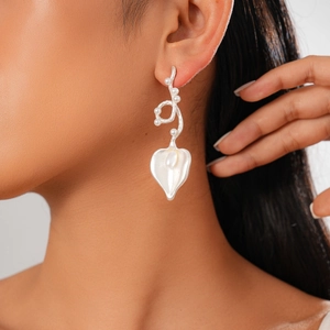 Close-up of model wearing silver heart leaf drop earrings with white pearls