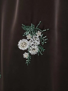 Vue détaillée de broderies florales faites main avec paillettes blanches sur satin foncé