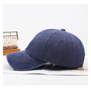 Close-up of washed denim baseball cap showing deep blue fabric texture and curved brim