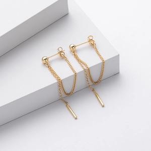 Macro view of gold S925 silver long drop earrings with double chains on white geometric props