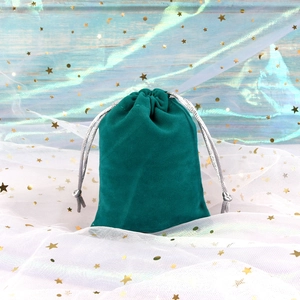 Detail of dark green velvet drawstring jewelry pouch with silver cords on star tulle
