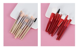 Detail of 8-piece wood handle and 7-piece red handle makeup brush sets on white trays