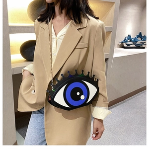 Detail of creative big eye crossbody bag with golden chain strap on a model wearing a suit