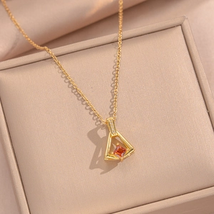 Detail of gold necklace with triangle pendant featuring orange gemstone and pavé zircon