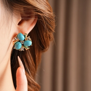 Gros plan de boucles d'oreilles fleur dorée avec turquoise et strass sur un mannequin