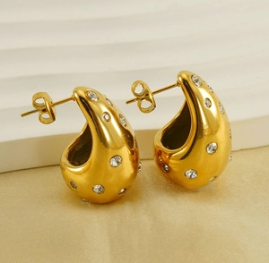 Macro shot of 18K gold water drop earrings with micro-pave crystals on white background