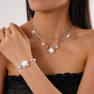 Dettaglio di un set collana e bracciale a doppio strato in argento con fiori e perle