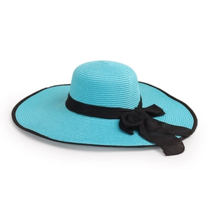 Detail of blue straw hat with black ribbon bow and textured woven pattern on white backdrop