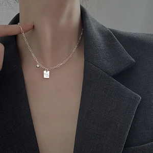 Detail of silver S925 necklace with Good Luck engraved square pendant on a model