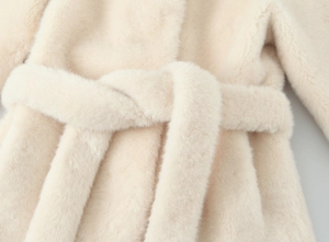 Detailed view of the faux fur jacket's cream-colored waist tie and plush texture