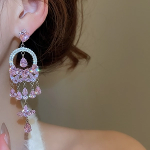 Close-up of pink zircon heart and tassel earrings on model with sparkling drop crystals