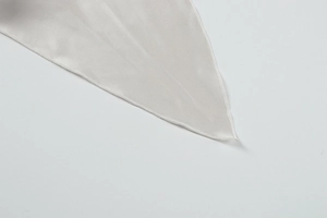 Detailed view of silver satin fabric with high-density lockrand edge and silk texture