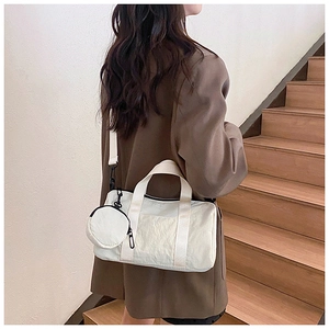 Detail of a minimalist white nylon tote bag with round coin purse on a stylish shoulder strap