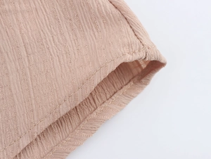 Vue macro du tissu texturé marron clair montrant les coutures fines et les plis