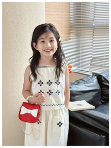 Detail of red mini crossbody bag with white bow and gold chain strap for kids