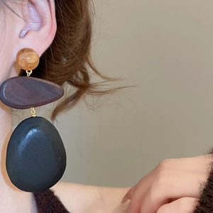 Close-up of vintage wood and resin drop earring with marble bead on model's ear
