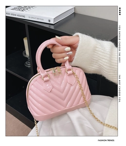 Detail of pink jelly shell bag featuring V-shaped texture and gold metal chain strap