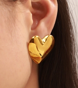 Makroaufnahme großer Herz-Ohrring aus 18k Gold mit polierter Oberfläche am Modell