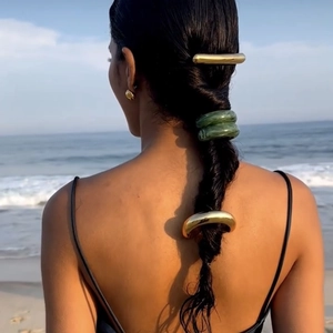 Retro golden hairpin and dark green elastic hair rings worn by model at the beach