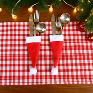 Detailed view of red and white mini Santa hat cutlery holders on a festive table mat