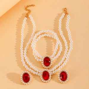 Détail d'une parure en perles avec pierres ovales rouges et accents en métal doré