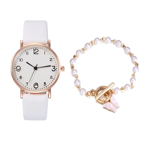 Close-up of white quartz watch set with elegant gold pearl bracelet and butterfly charm