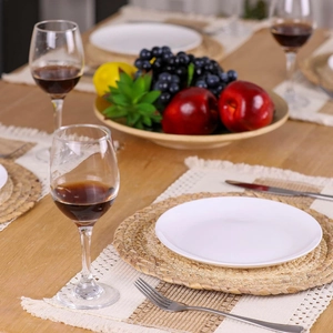 Detailed view of woven seagrass placemat with white ceramic plate on wooden table