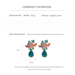 Detailed view of blue zircon teardrop earrings with butterfly accents in copper and gold