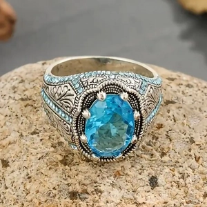 Vista macro di un anello vintage in argento con gemma ovale blu chiaro e incisioni floreali