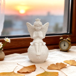 Detailed view of white angel figurine with wings and crown on decorative floral sphere