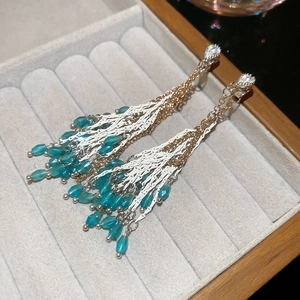Gros plan de boucles d'oreilles à pompons avec perles bleues et strass en cristal
