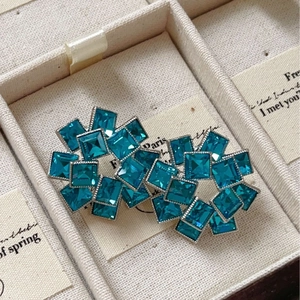 Blue square zircon floral earrings with geometric hollow design on a beige jewelry card