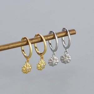 Detailed macro view of gold and silver flower hoop earrings with center crystal accent
