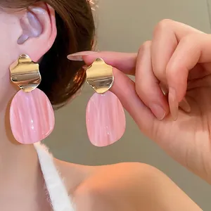 Irregular oval earrings with pink marble resin pendants and golden wavy metal details