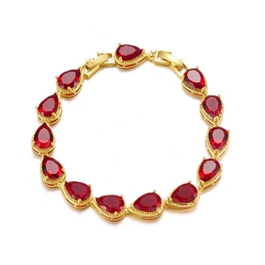 Macro detail of gold-plated bridal bracelet featuring vivid red pear-cut cubic zirconia stones
