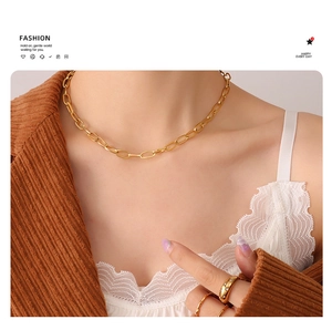 Detail showing gold paperclip chain necklace styled with matching ring on model