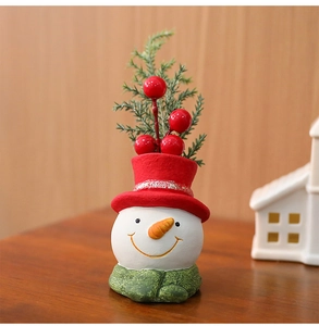 Detail of Christmas snowman figurine with red hat, green scarf and pine needle accents
