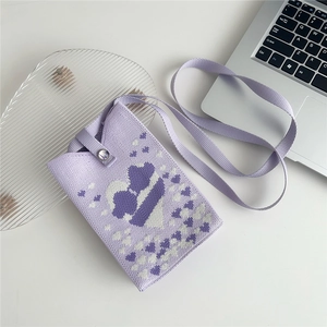 Detail of purple knitted phone bag featuring white heart patterns and a snap closure